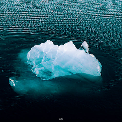 Large iceberg floating in the ocean with a dark blue water background
