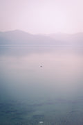 Hazy landscape with mountains and a small island in the distance.