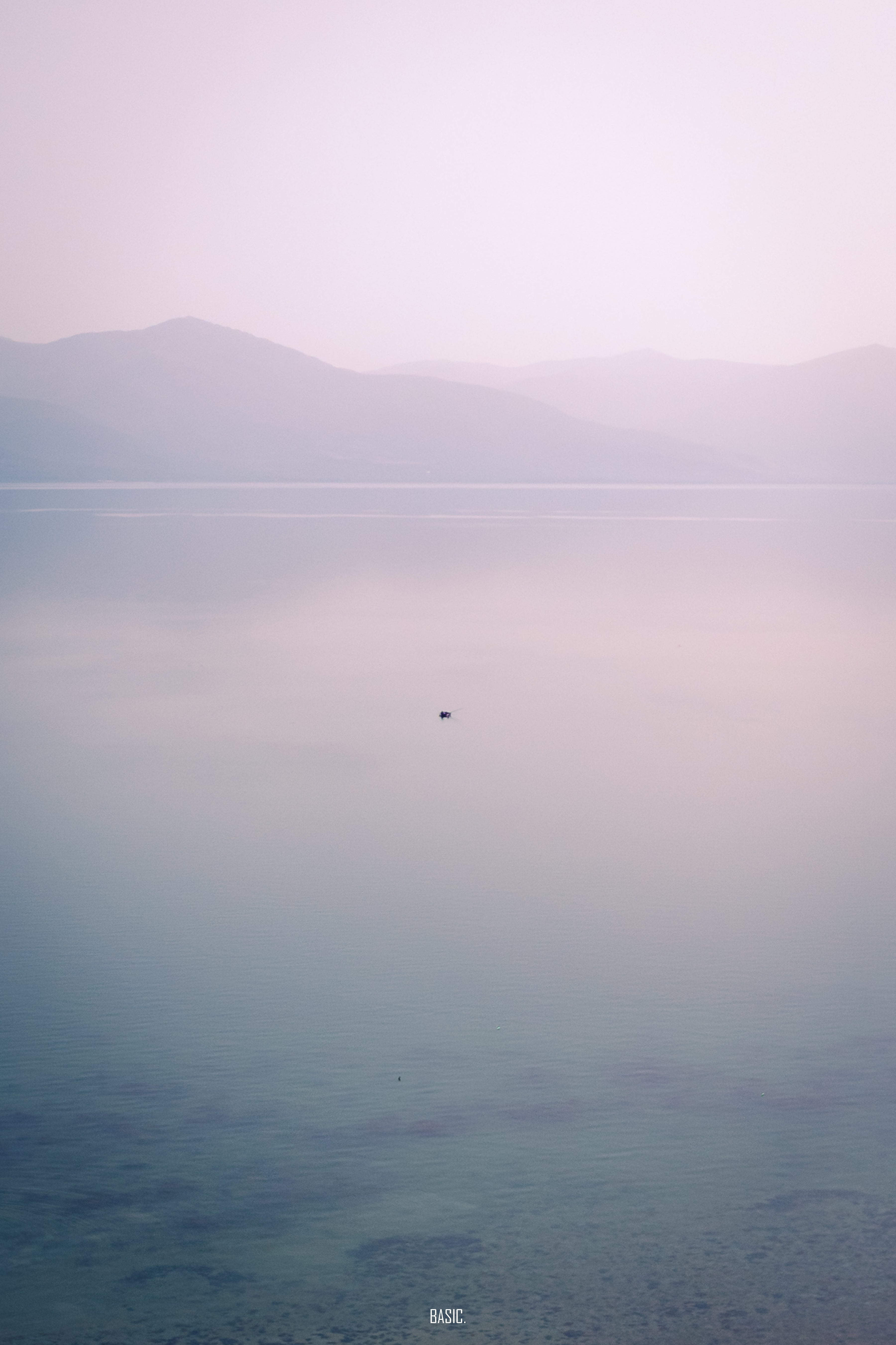 Hazy landscape with mountains and a small island in the distance.