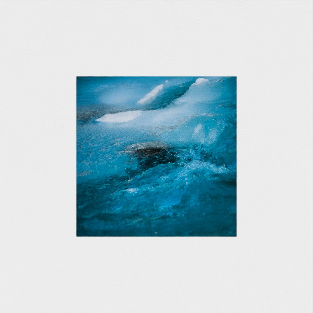 A square art print depicting a close-up of swirling blue ice and water with white foam, centered on a light gray background.