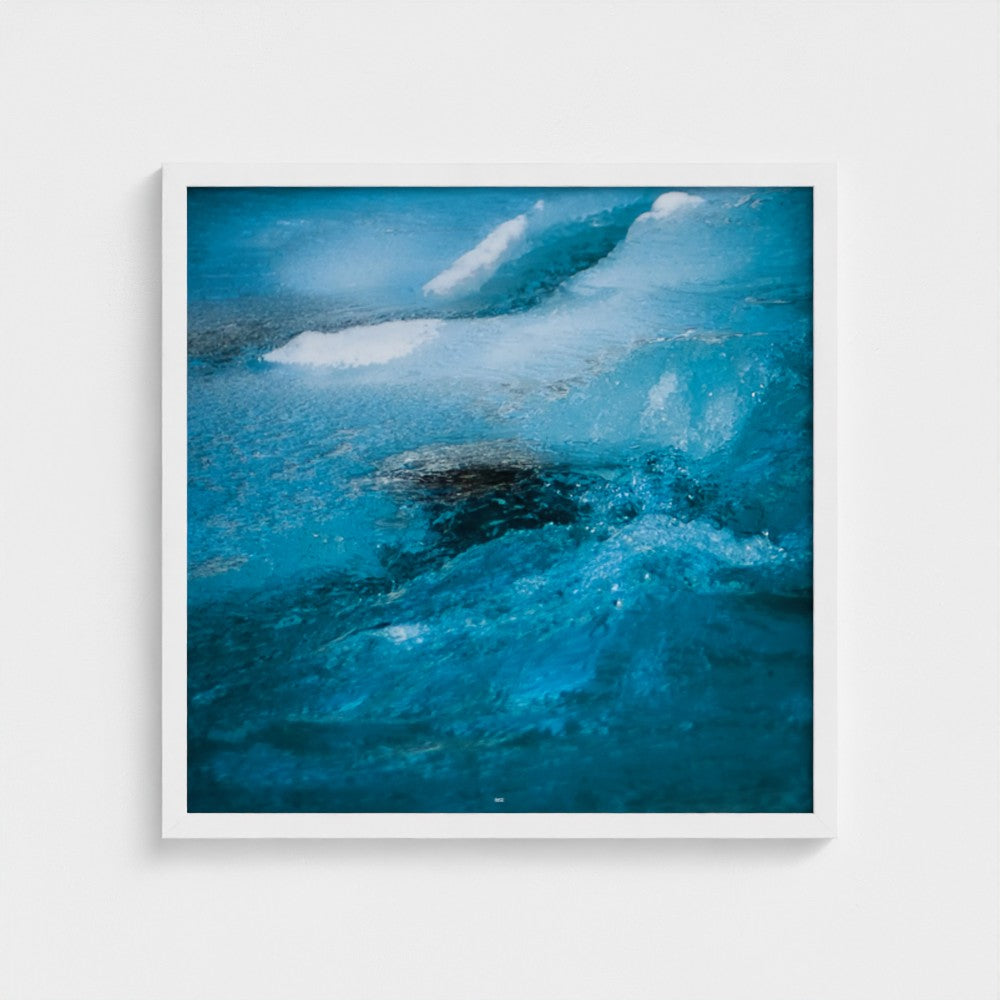 A framed square art print depicting a close-up abstract ocean wave in vivid blue and turquoise tones with white foam, displayed against a light gray wall.