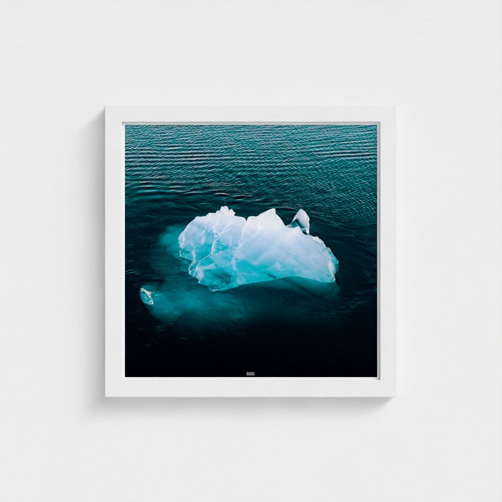 Framed photograph of an iceberg in the ocean on a white wall