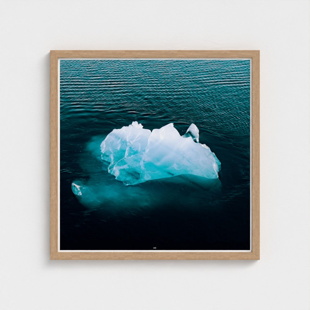 Framed photograph of an iceberg floating in water on a white wall
