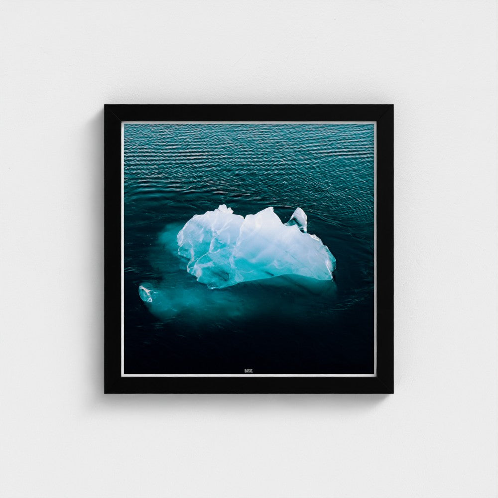 Framed photograph of an iceberg floating in water on a white wall