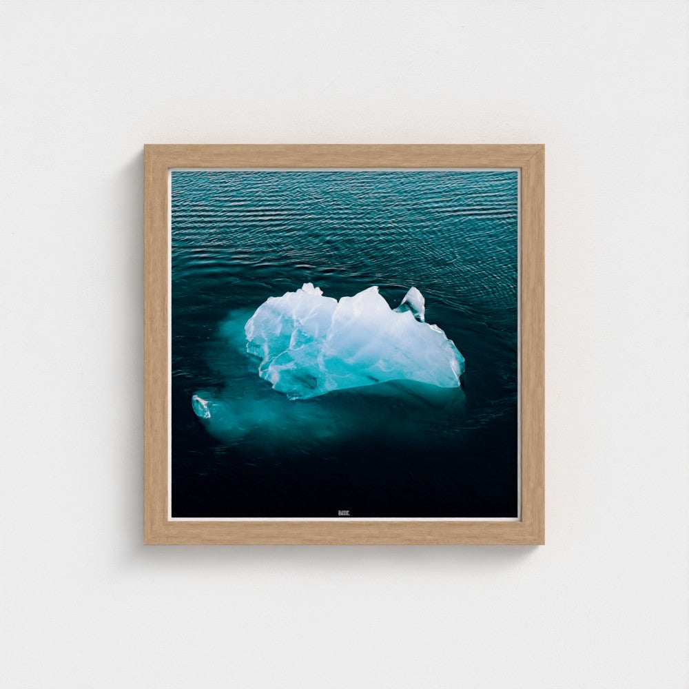 Framed photograph of an iceberg in water on a white wall