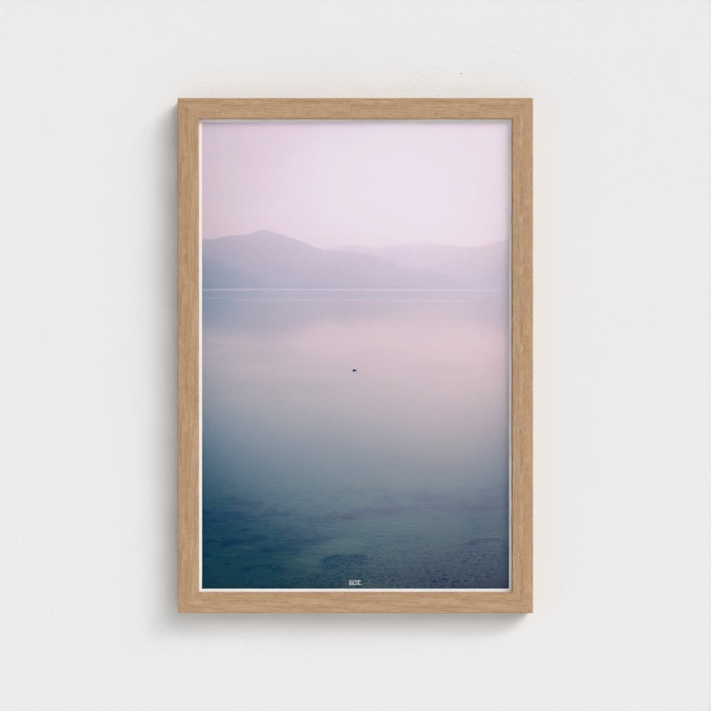 Framed artwork of a mountain and water landscape on a white wall
