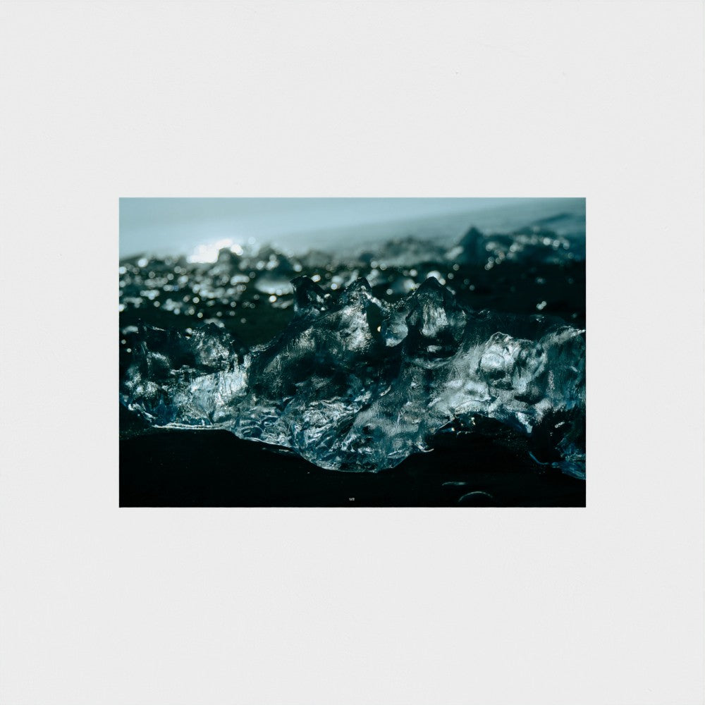 A square photographic print of a close-up icy or crystalline landscape in deep blue, teal, and black tones, centered on a light gray background.