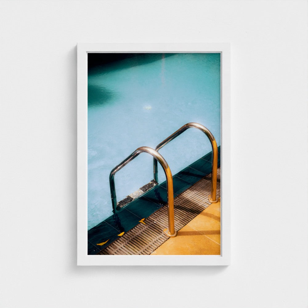 Framed photograph of a pool with a metal ladder on a white background