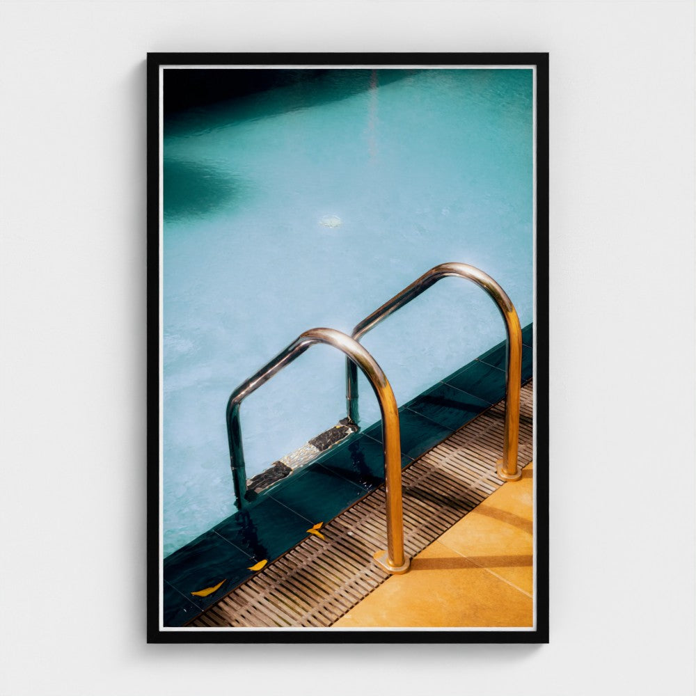 Framed photograph of a pool ladder with clear water and blue sky.