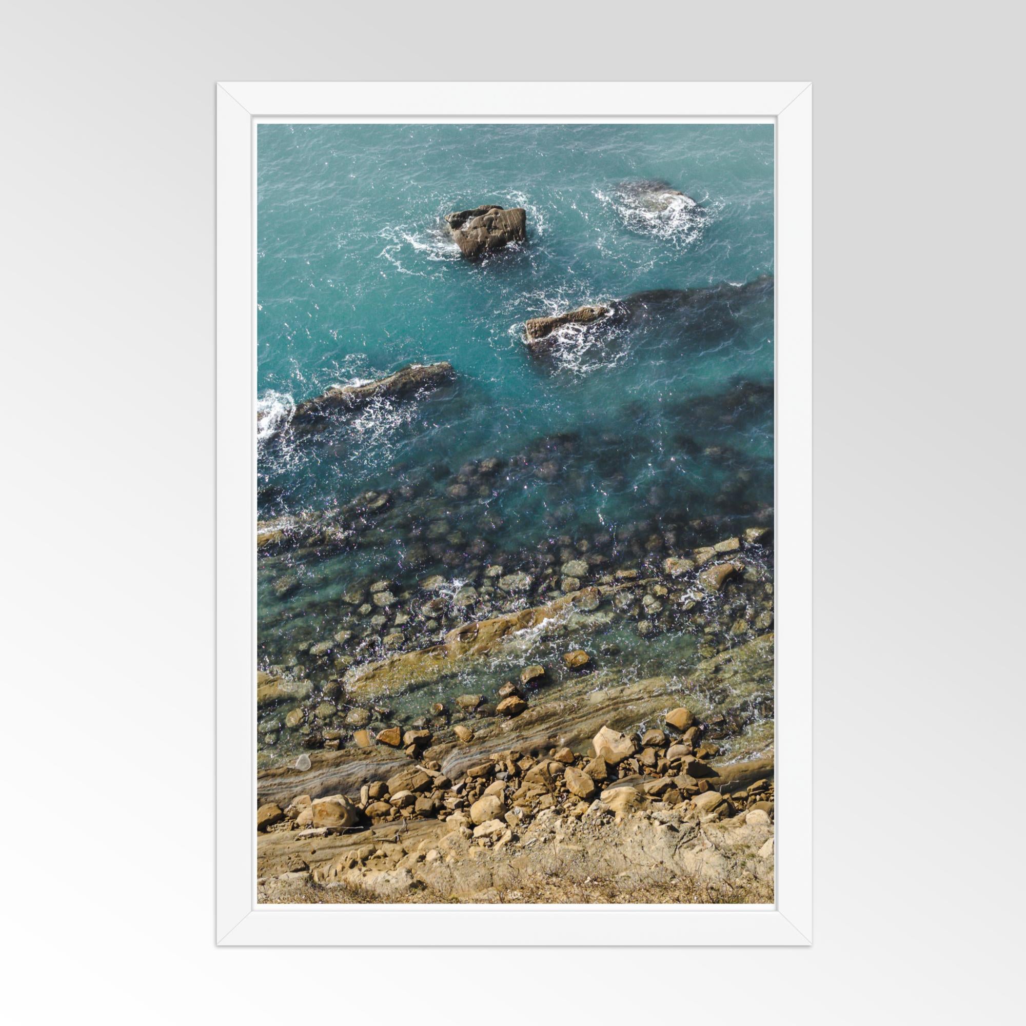 Rocks and waves in a coastal scene with a white frame.