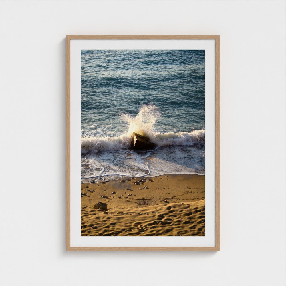 Framed photograph of a beach scene with waves crashing onto the shore.