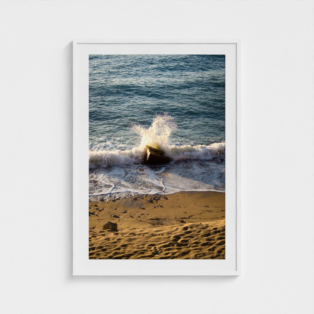 Framed photograph of a wave crashing on a beach with a white frame.