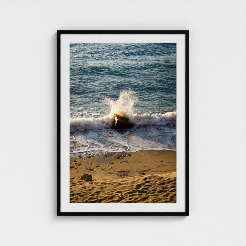 Framed photograph of a beach scene with waves crashing onto the shore.
