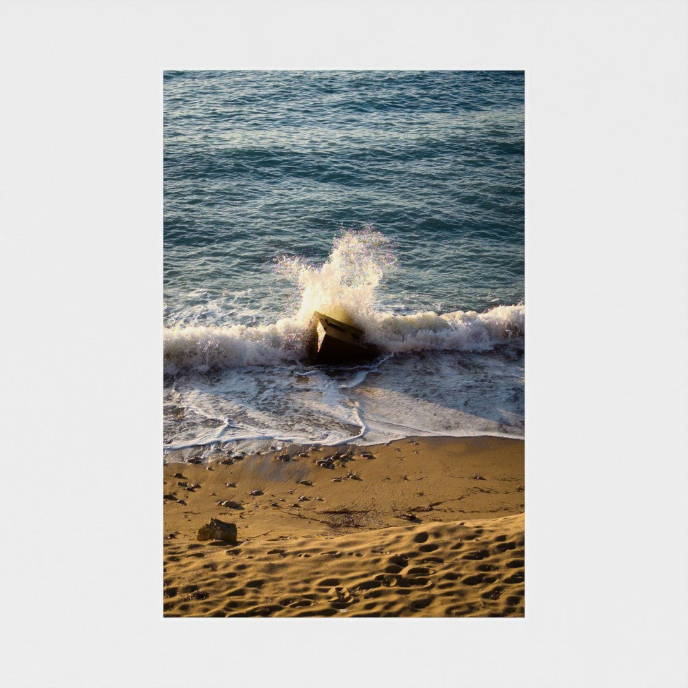 Wave crashing onto a rocky beach with ocean water and sand visible
