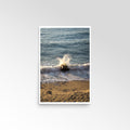 Framed photograph of a wave crashing on a beach with a white border.