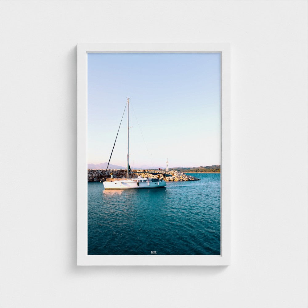 Framed photograph of a sailboat on calm water with a clear sky.