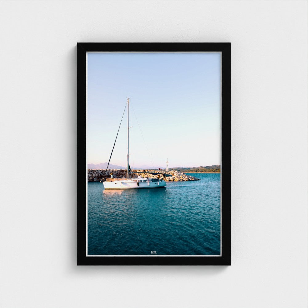 Framed photograph of a sailboat on a body of water with a clear sky.