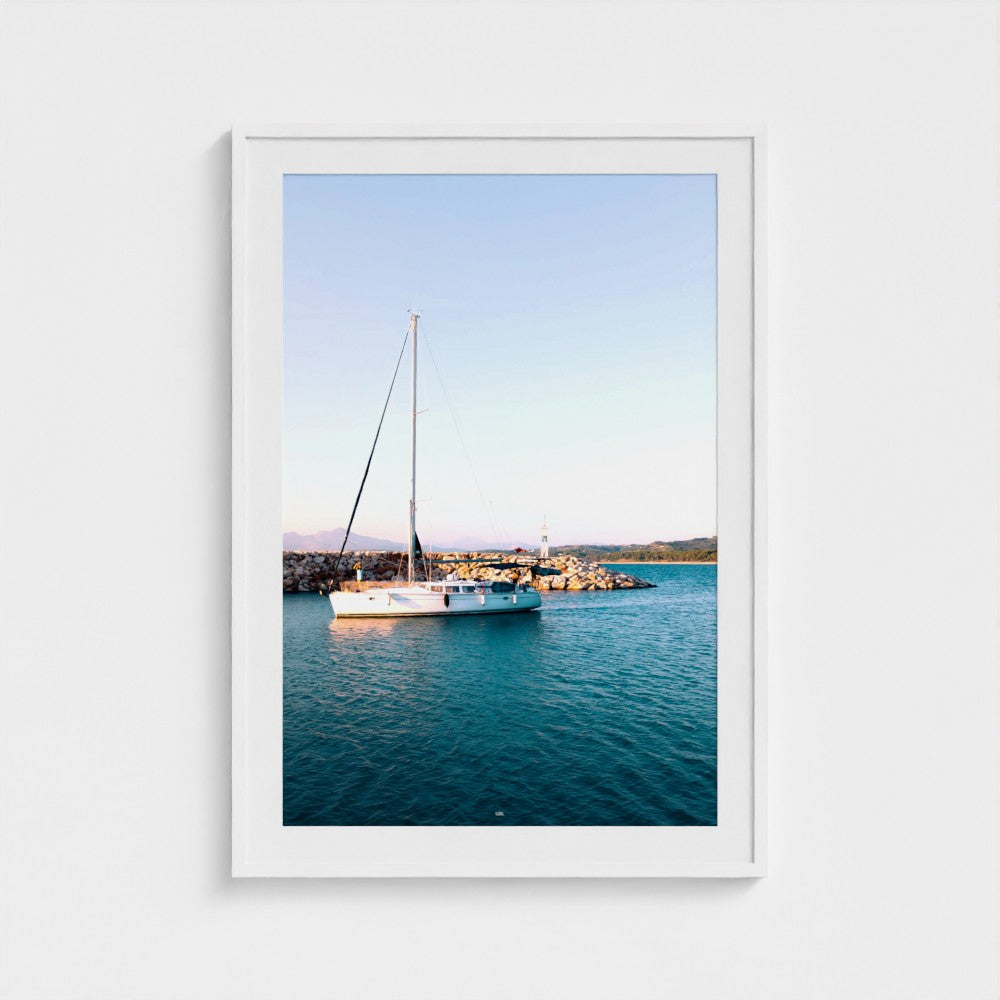 Framed photograph of a sailboat on a body of water with a white frame.