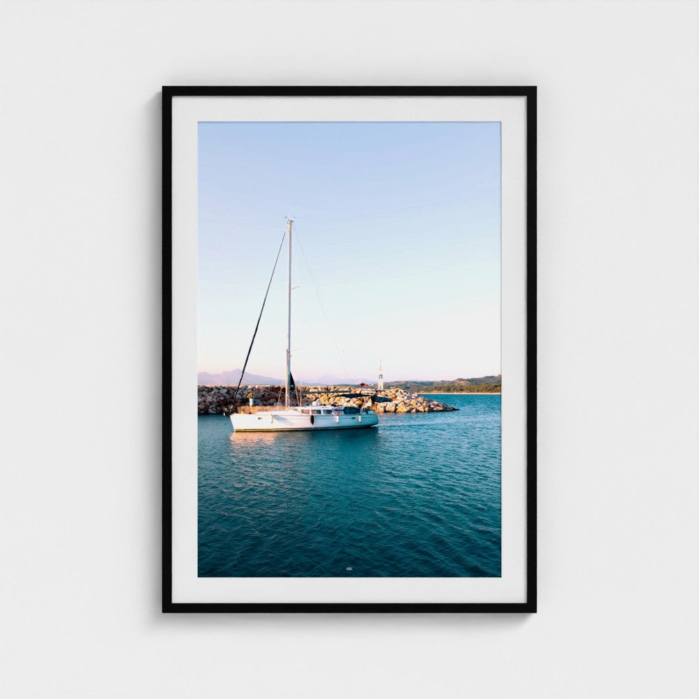 Framed photograph of a sailboat on a body of water with a clear sky.