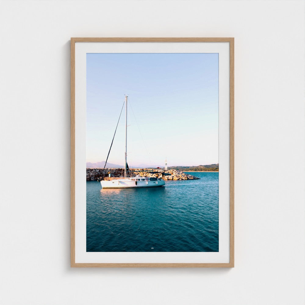 Framed photograph of a sailboat on a body of water with a clear sky.