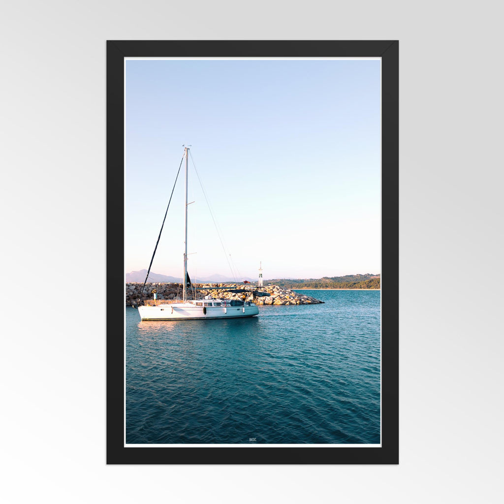 Framed photograph of a sailboat on calm water with a clear sky.
