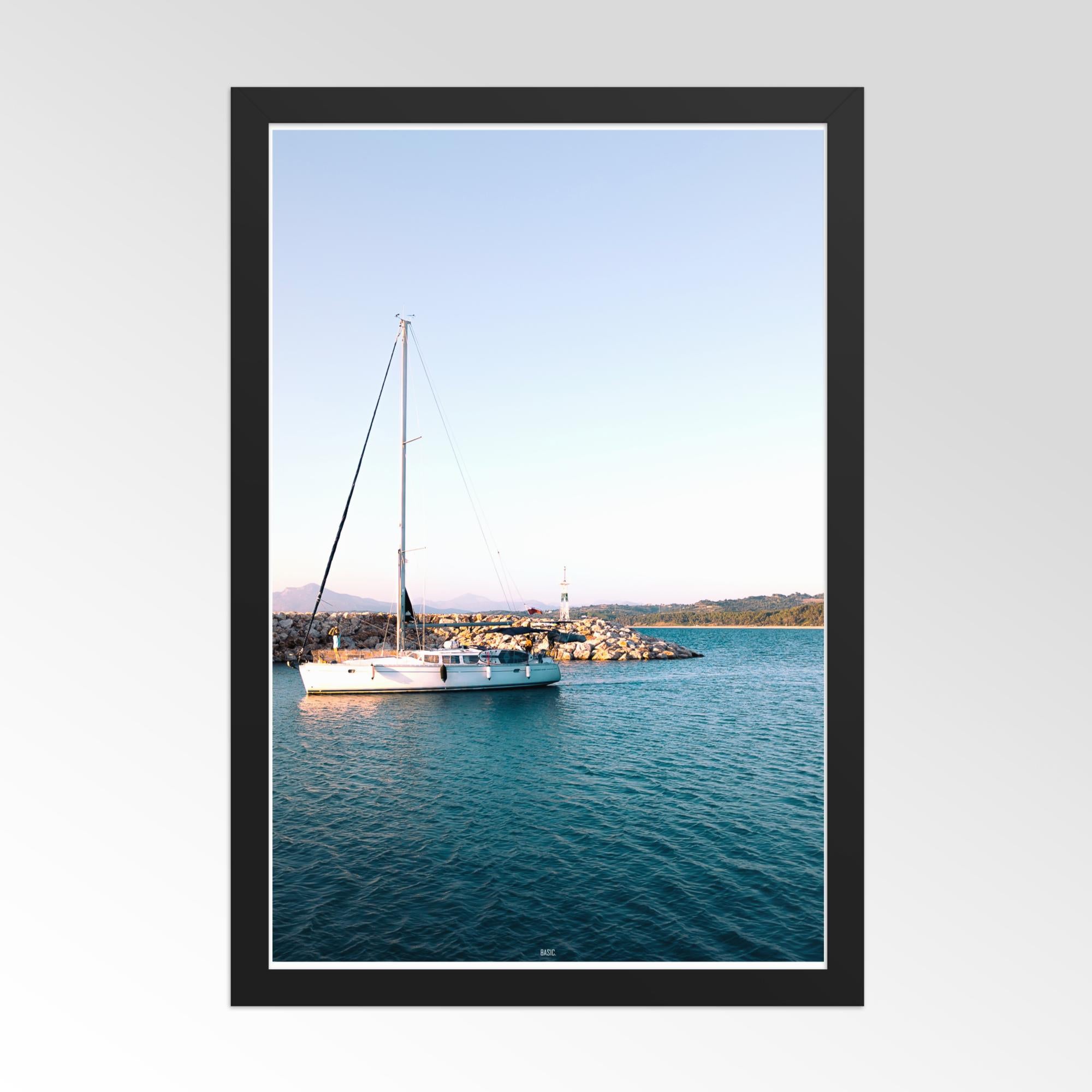 Framed photograph of a sailboat on calm water with a clear sky.