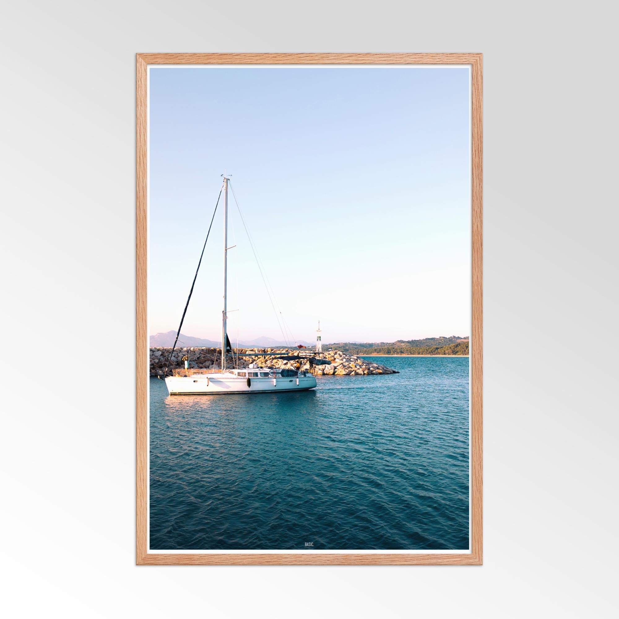 Framed photograph of a sailboat on a body of water with a coastal view.