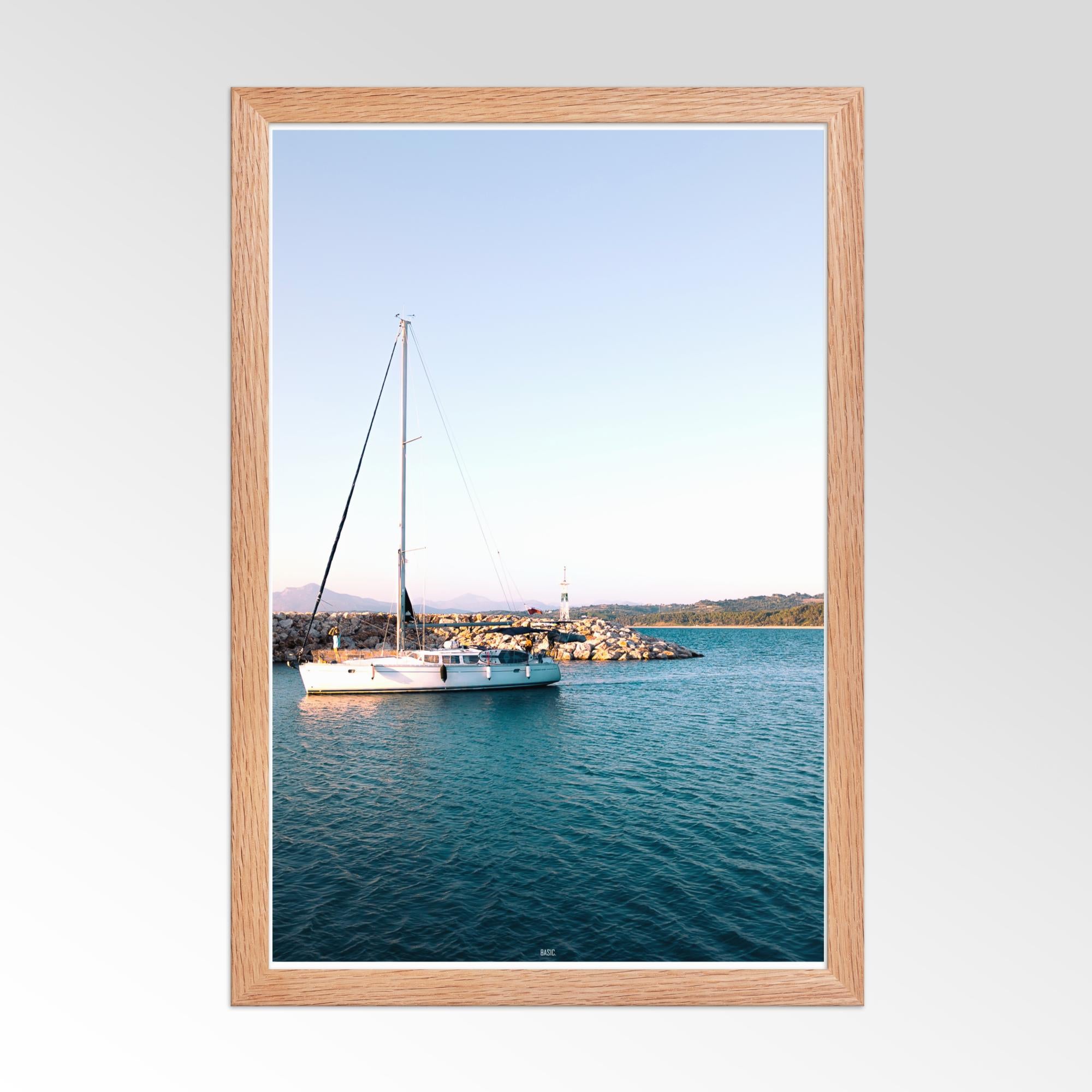 Framed photograph of a sailboat on calm water with a wooden frame.
