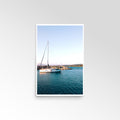 Framed photograph of a sailboat on calm water with a clear sky.